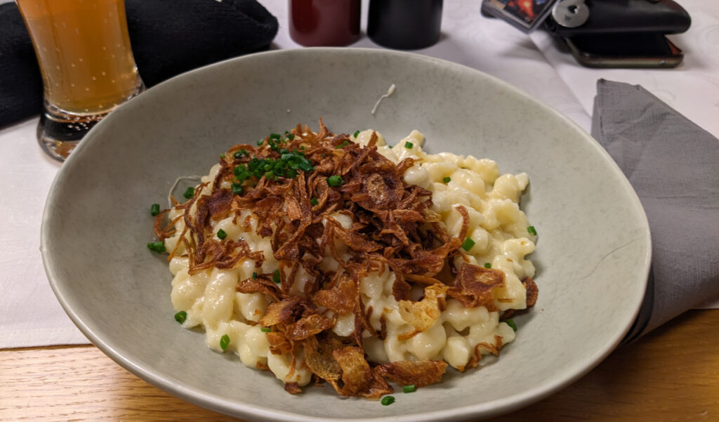 A plate with Spätzle, a kind of pasta with melted cheese, chive, roasted onions on top